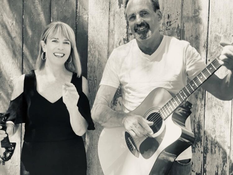 Image of two musicians, a female and a male holding a guitar. The image is black and white.
